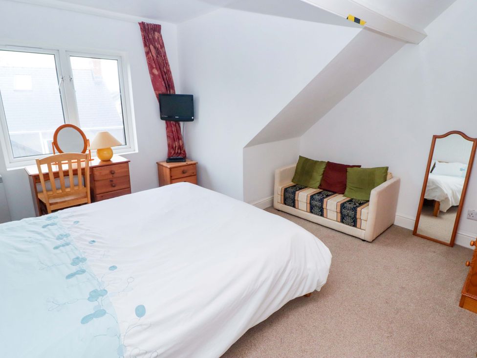 A bedroom with a bed and a chair at Gwylan Maisonette in Tenby