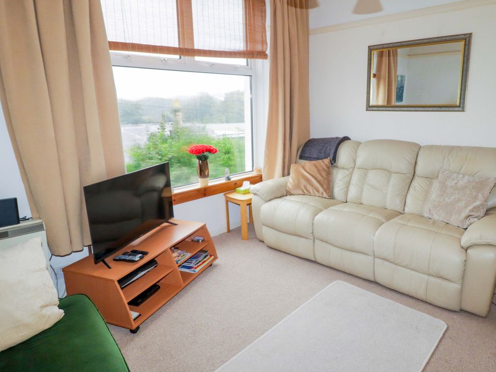 A living room with a sofa and television at Gwylan Maisonette in Tenby