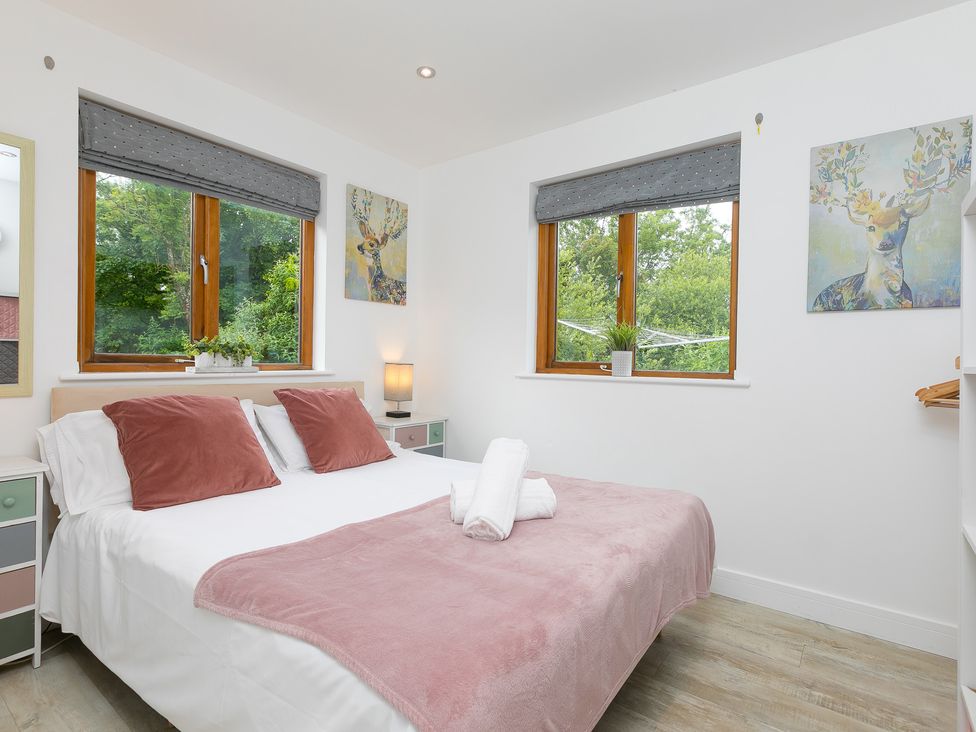 A bedroom with a bed and windows at Branock, Tor Down Quarry in St Breward