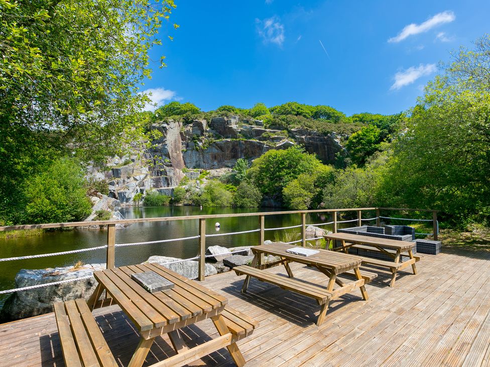 An outdoor area with wooden tables and a view of water and rocks at Branock, Tor Down Quarry St Breward