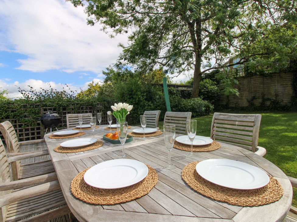 An outdoor dining table set with plates and glasses at Welsummer Salcombe