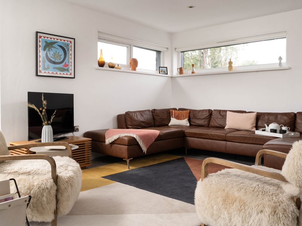 A living room with a sectional sofa and television at Estuary Watch in Lelant near Carbis Bay