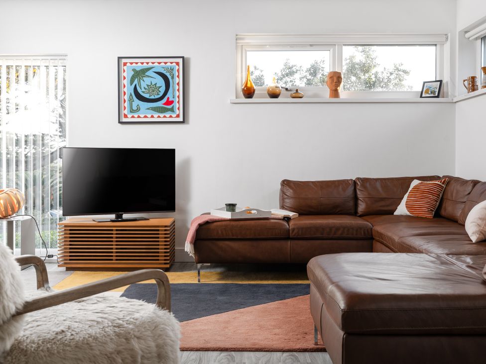 A living room with a television and a brown sofa at Estuary Watch in Lelant near Carbis Bay