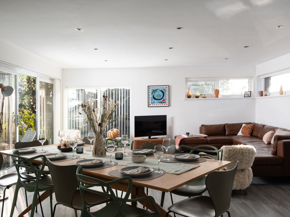 A dining room with a table set and a sofa at Estuary Watch in Lelant near Carbis Bay