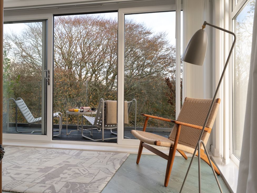 A sunroom with a chair and a lamp at Estuary Watch Lelant near Carbis Bay