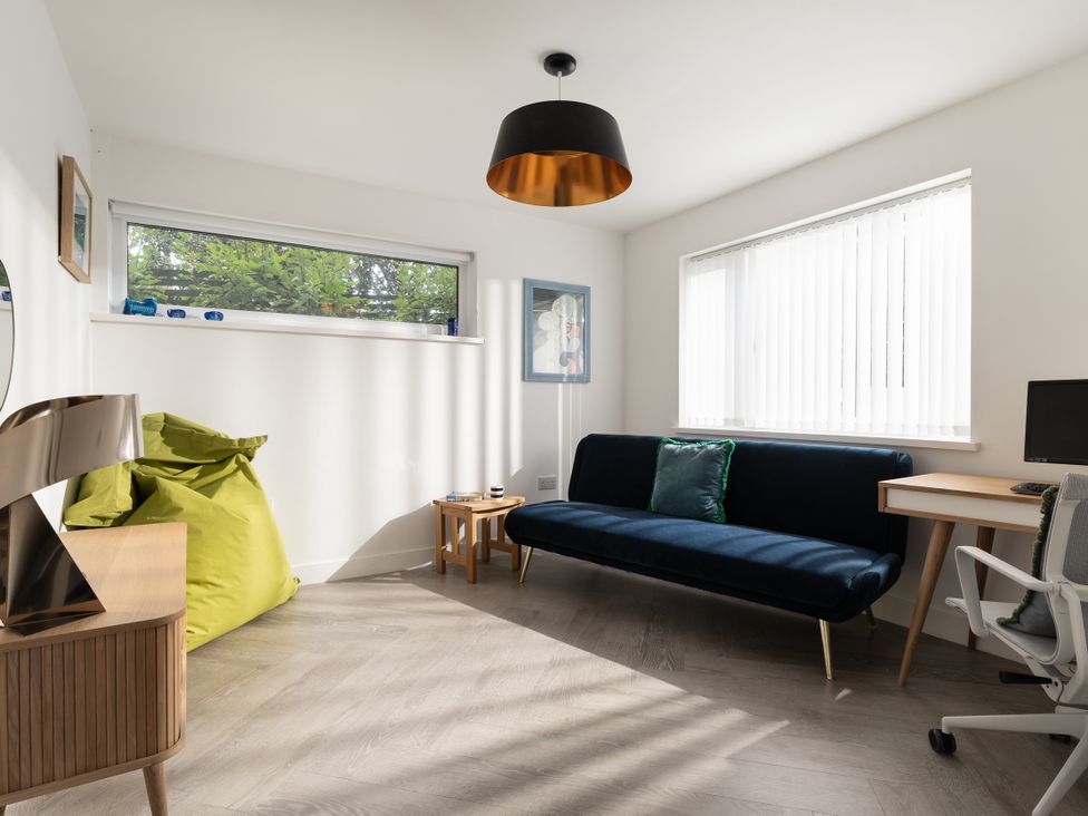 A living room with a sofa and desk at Estuary Watch in Lelant near Carbis Bay