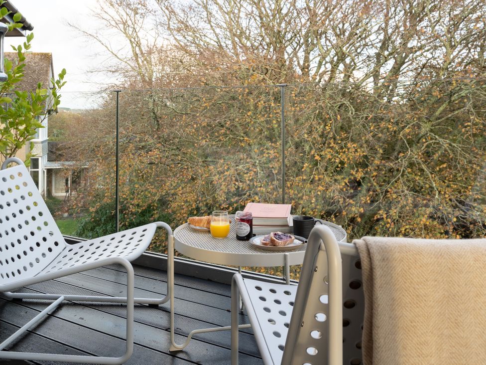 A balcony with chairs and a table with food and drinks at Estuary Watch in Lelant near Carbis Bay