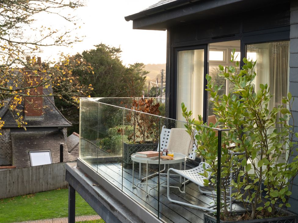 A balcony with glass railing and plants at Estuary Watch in Lelant near Carbis Bay