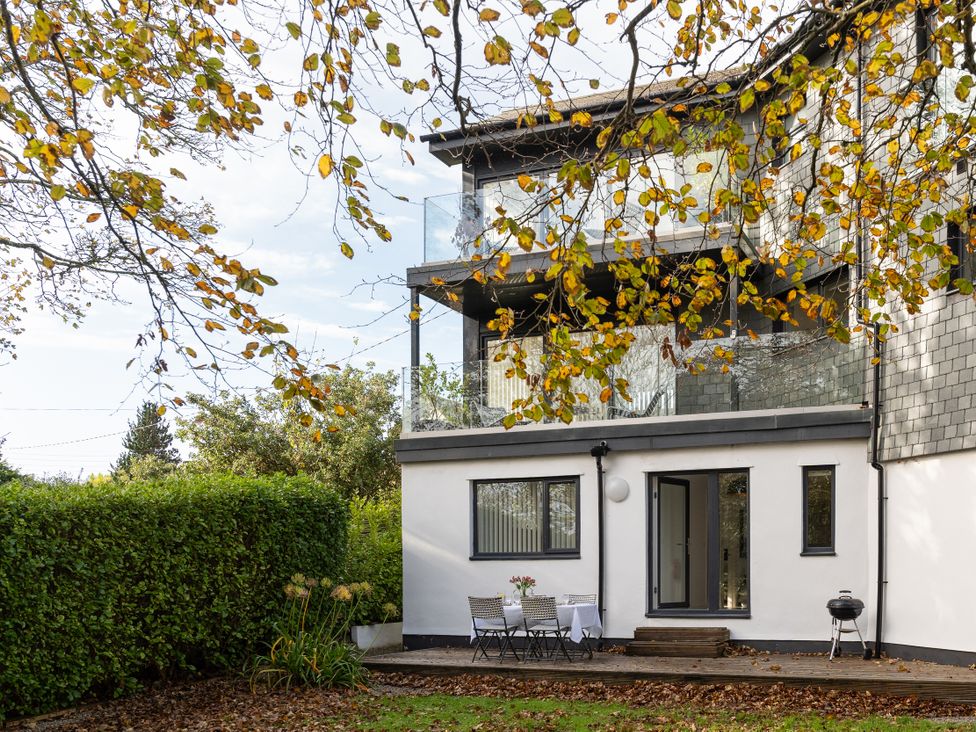 An outdoor area with a table and chairs near a house at Estuary Watch Lelant near Carbis Bay