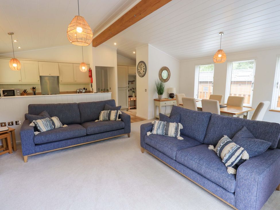 A living room with two blue sofas and dining table with chairs at Hollytree Lodge Beckside 1 Limefitt Park near Windermere