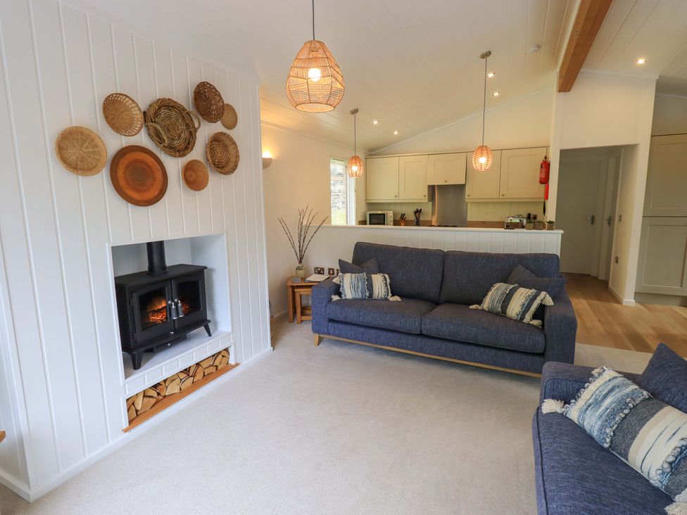 A living room with a firewood stove and blue sofas at Hollytree Lodge Beckside 1 Limefitt Park near Windermere
