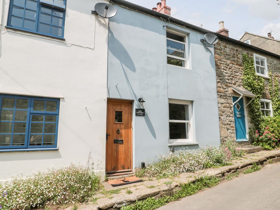 An exterior view of a cottage with flowers and stones at Lea Cottage in Eype