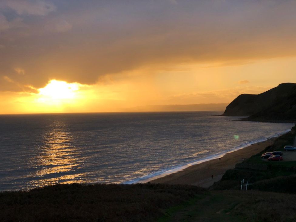 A sunset over the sea viewed from a beach at Lea Cottage Eype