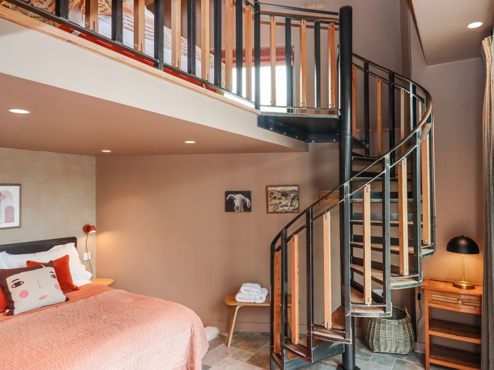 A bedroom with a spiral staircase and a bed at 3 Caddaford Barns in Buckfastleigh