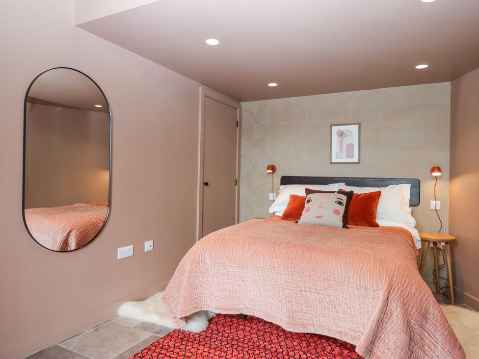 A bedroom with a bed, mirror, and nightstand at 3 Caddaford Barns, Buckfastleigh
