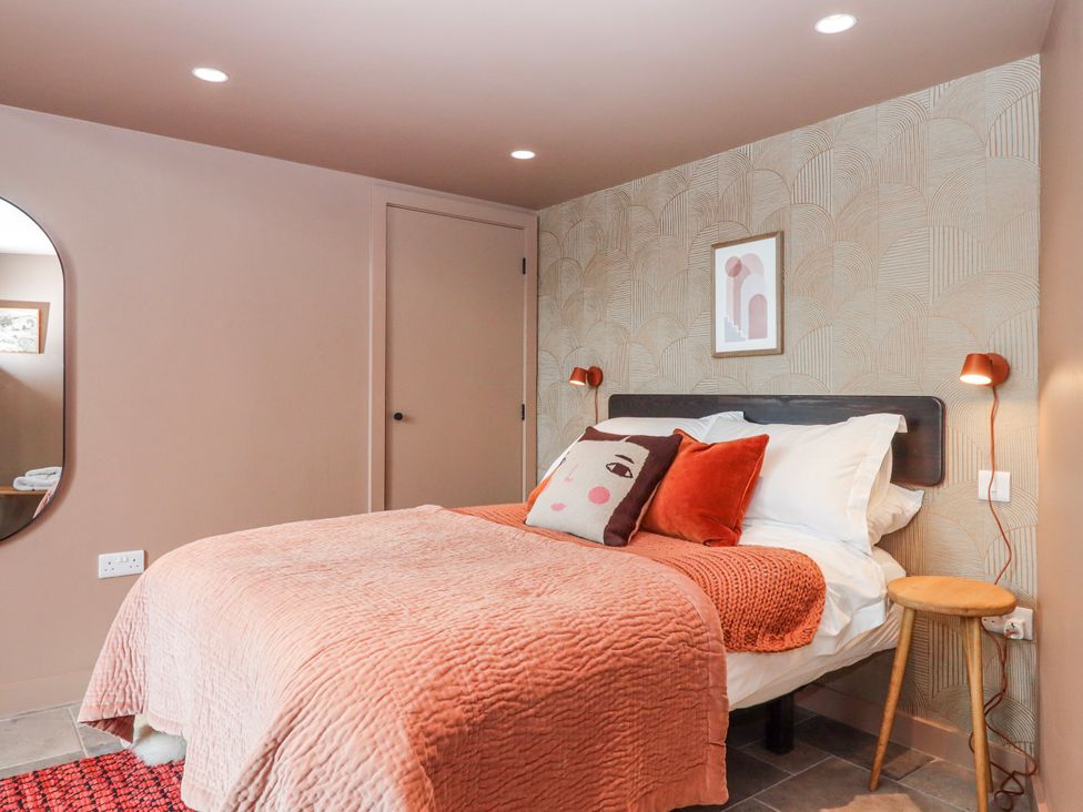 A bedroom with a bed and wall art at 3 Caddaford Barns in Buckfastleigh