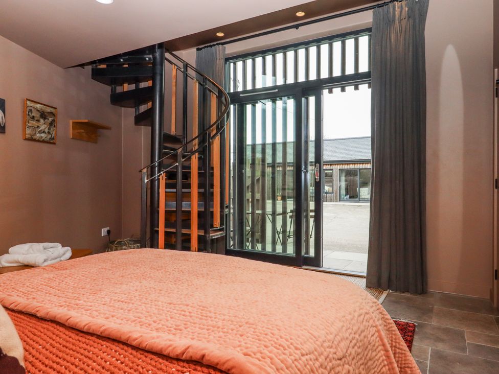 A bedroom with a spiral staircase leading to an outdoor area at 3 Caddaford Barns Buckfastleigh