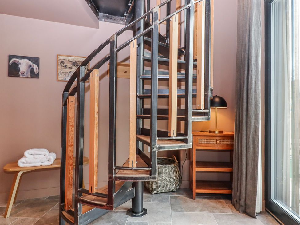 A hallway with a spiral staircase and a shelf at 3 Caddaford Barns Buckfastleigh