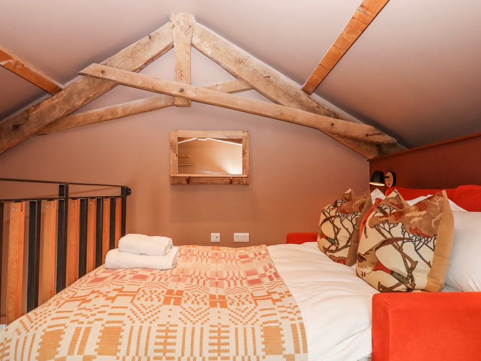 A bedroom with a bed and cushions at 3 Caddaford Barns Buckfastleigh