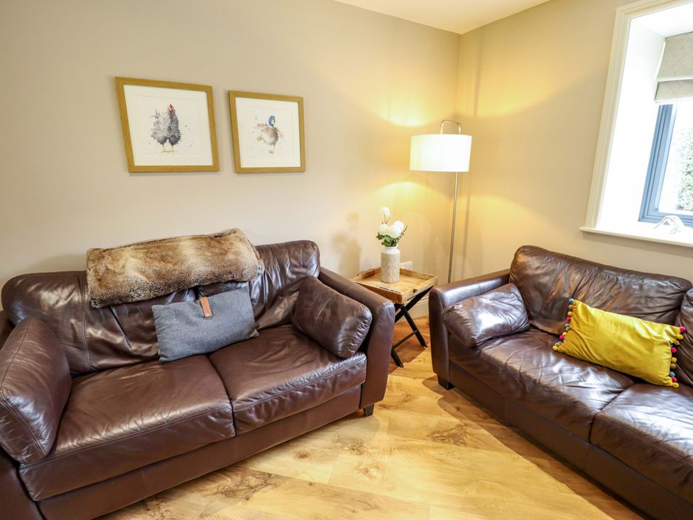A living room with brown leather sofas and art on the wall at Fox's Den in Burton Pidsea