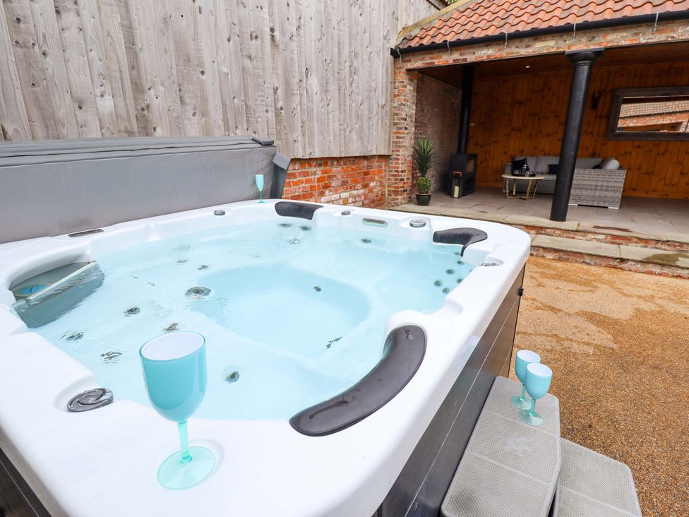 A hot tub with glasses on steps at Fox's Den in Burton Pidsea