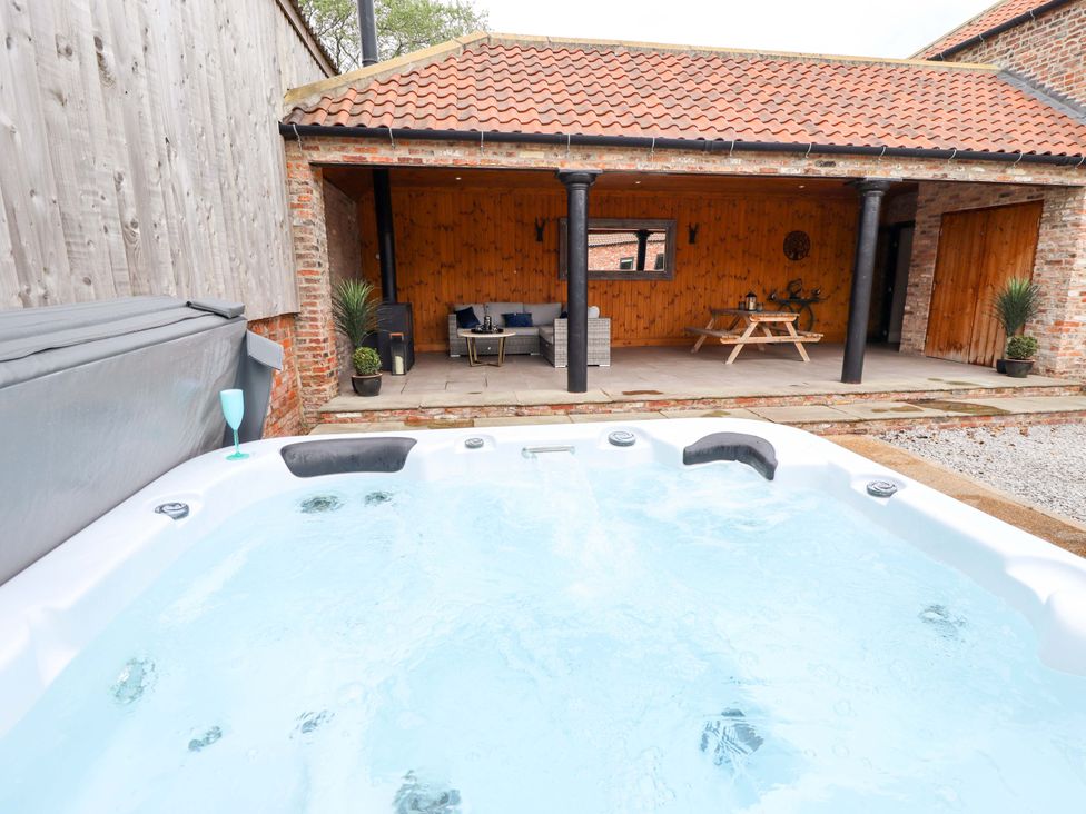 An outdoor area with a hot tub and seating at Fox's Den in Burton Pidsea