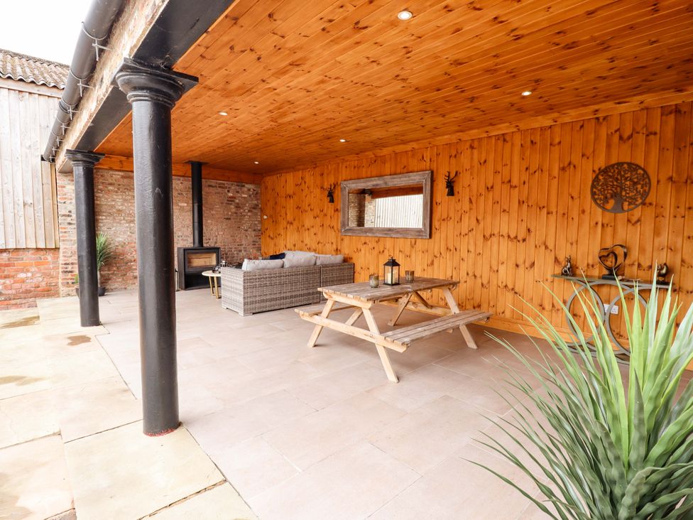 An outdoor seating area with a sofa and dining table at Fox's Den in Burton Pidsea