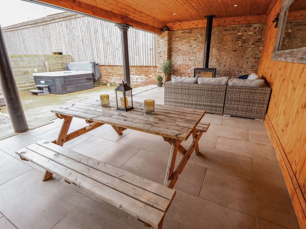 An outdoor area with a wooden table and benches at Fox's Den in Burton Pidsea