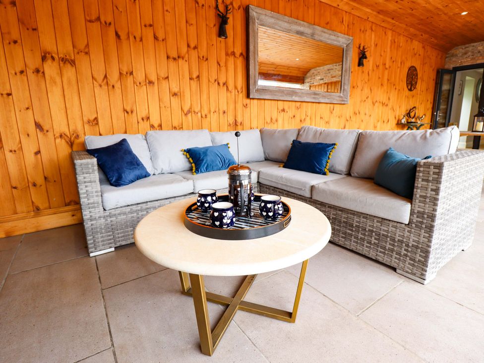 An outdoor seating area with a sofa and coffee table at Fox's Den in Burton Pidsea