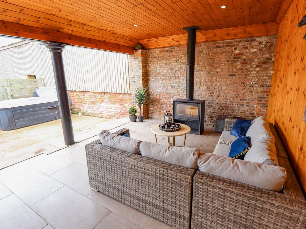 An outdoor seating area with a sofa and a wood stove at Fox's Den in Burton Pidsea