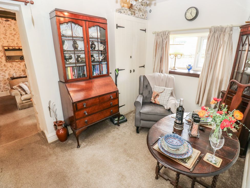 A living room with a bookshelf and dining table at Prospect Cottage in Ripponden