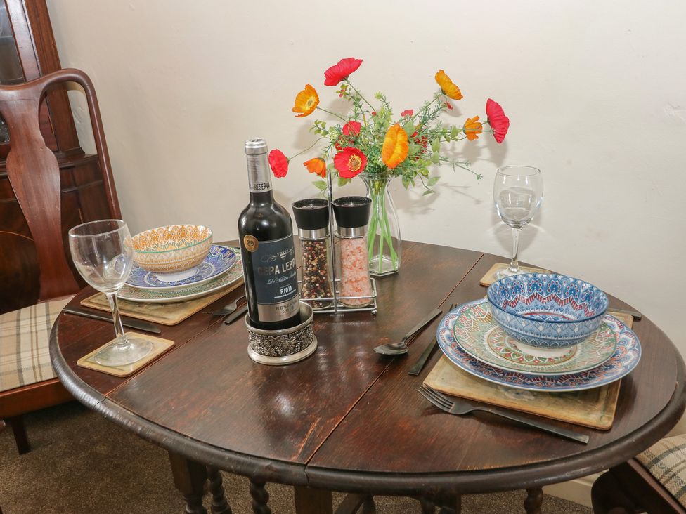 A dining table set with wine, glasses, plates and flowers at Prospect Cottage in Ripponden