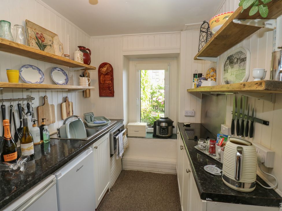 A kitchen with shelves, sink, and cooking appliances at Prospect Cottage in Ripponden