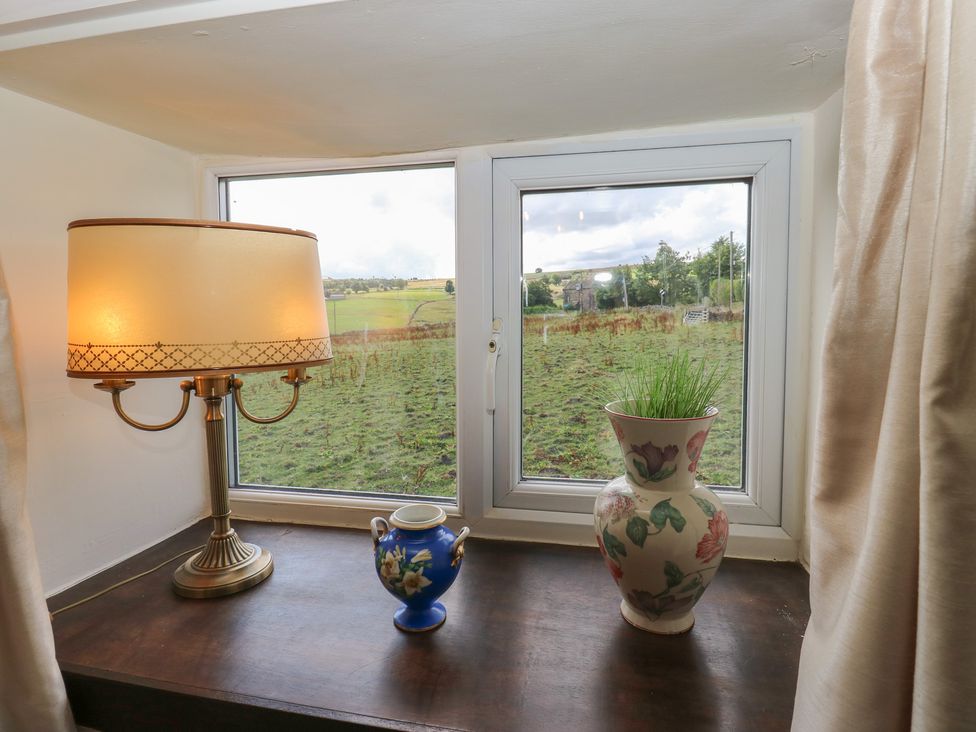 A window with a lamp and vases on the sill at Prospect Cottage in Ripponden