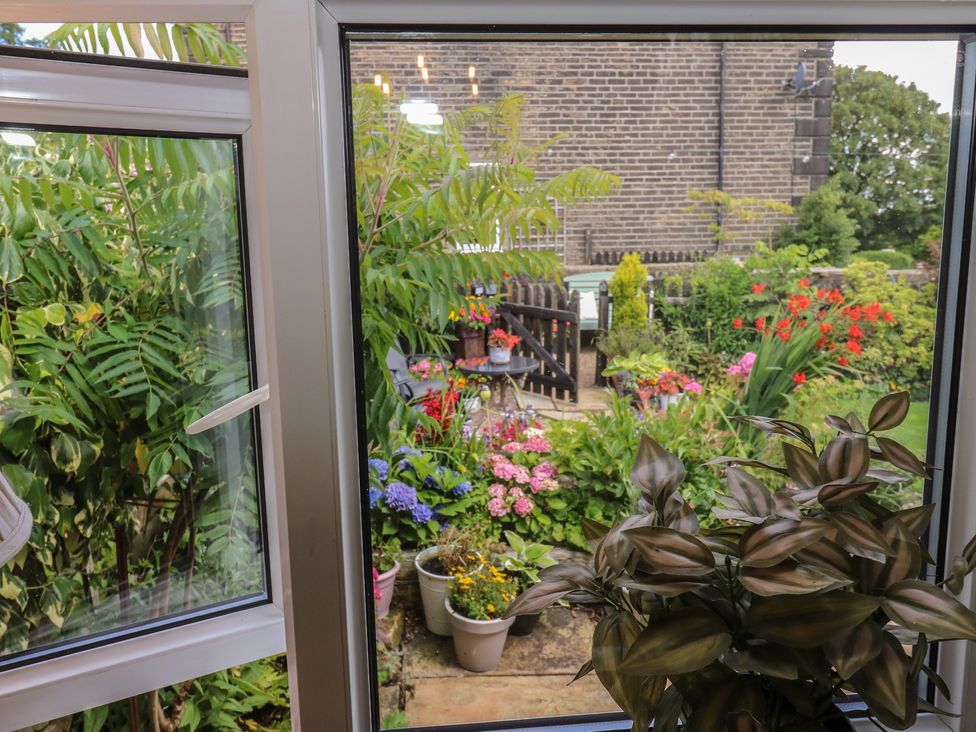 A view of a garden with flowers and plants from a window at Prospect Cottage in Ripponden