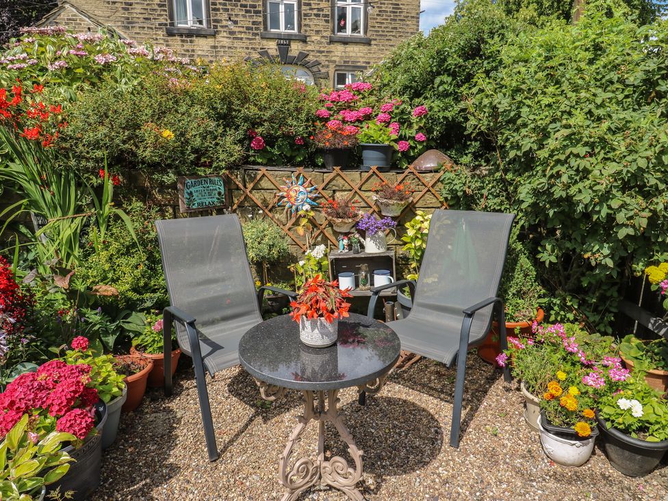 A garden with a table and chairs surrounded by flowers at Prospect Cottage in Ripponden