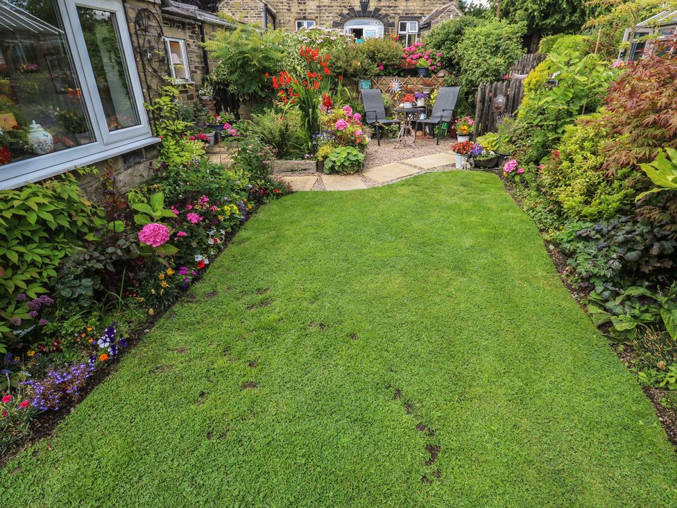 A garden with a lawn and flower beds at Prospect Cottage in Ripponden