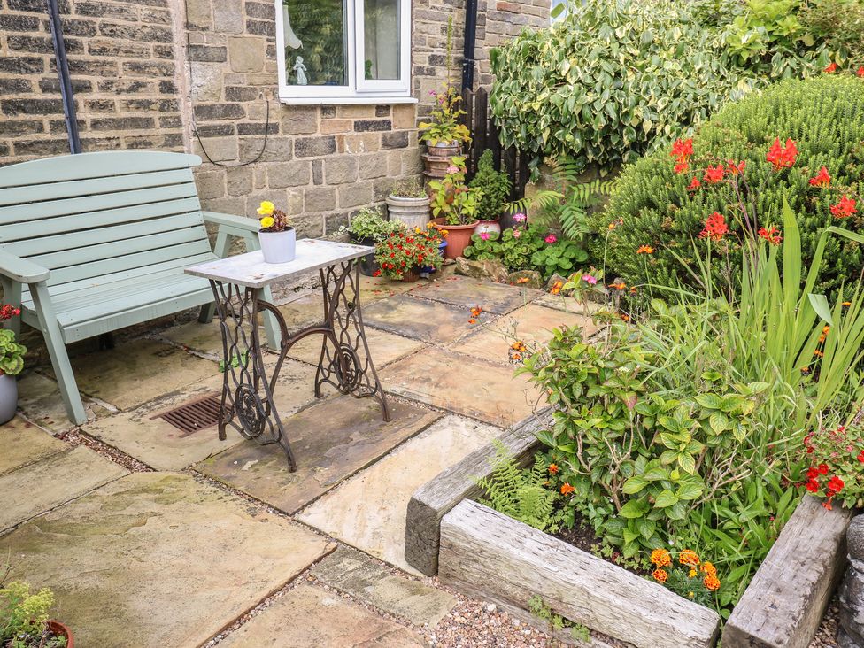 A garden with a bench and a table at Prospect Cottage in Ripponden