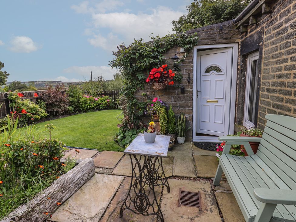 A garden area with a table and bench at Prospect Cottage in Ripponden