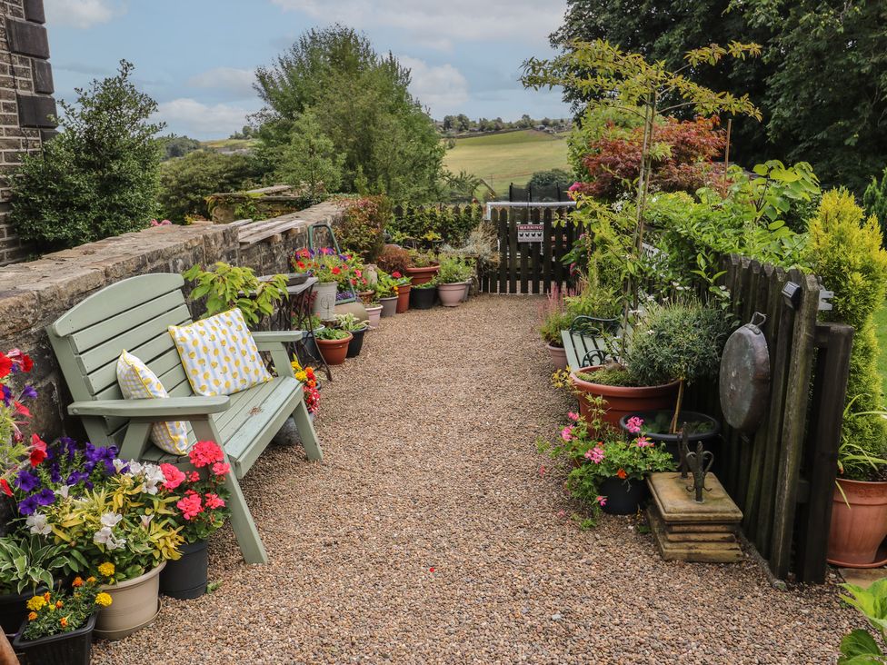 A garden path with flowers and a bench at Prospect Cottage Ripponden