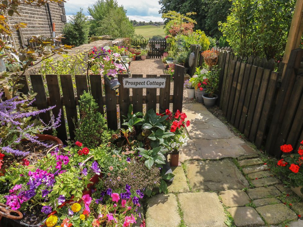 A garden pathway with flowers and a sign at Prospect Cottage in Ripponden