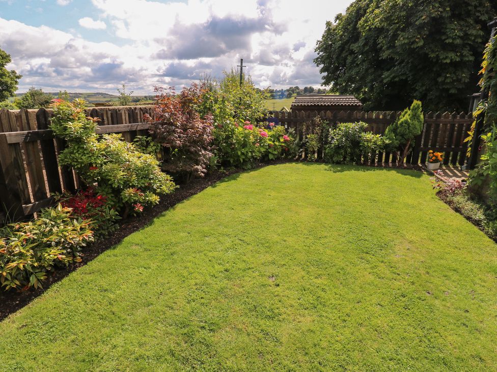 A garden with grass and flowerbeds at Prospect Cottage in Ripponden