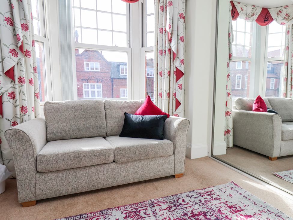 A living room with a sofa and a mirror at 50 West Street Edelweiss Scarborough