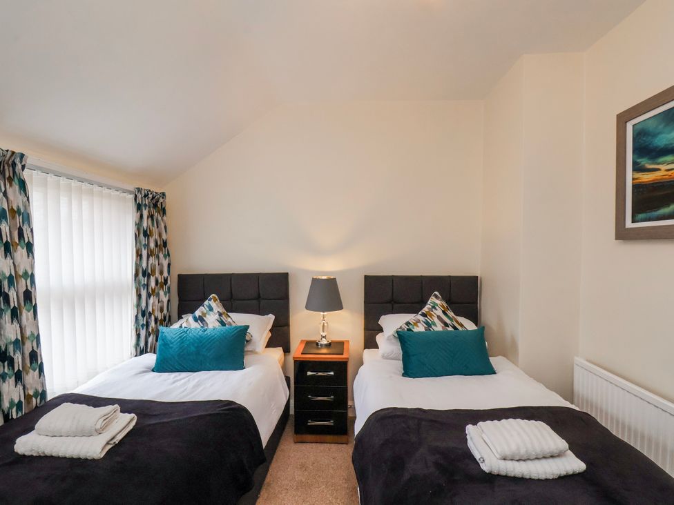 A bedroom with two beds and a nightstand at 50 West Street Edelweiss Scarborough