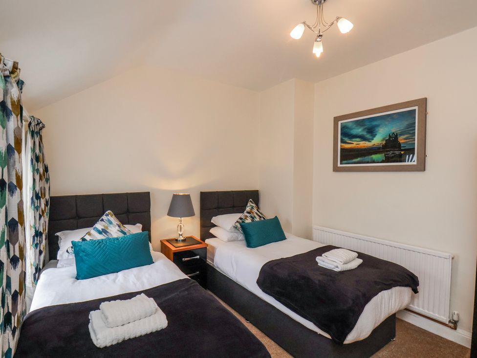 A bedroom with two beds and decorative items at 50 West Street Edelweiss in Scarborough