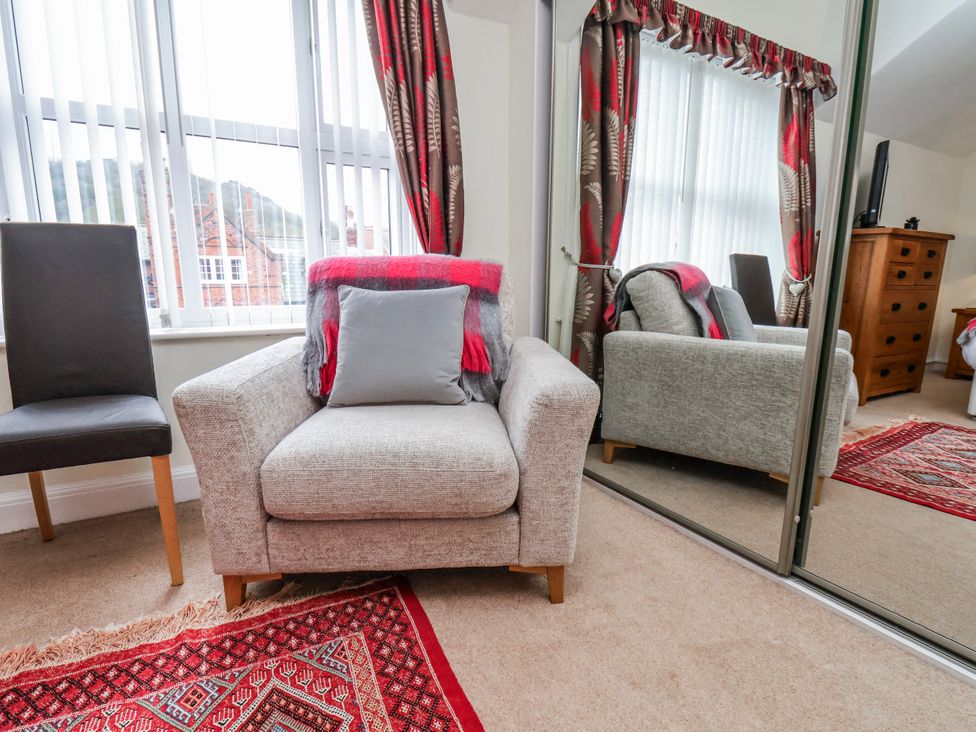 A living room with an armchair and a mirror at 50 West Street Edelweiss in Scarborough
