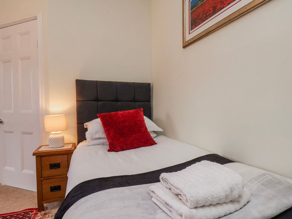 A bedroom with a single bed and bedside table at 50 West Street Edelweiss Scarborough