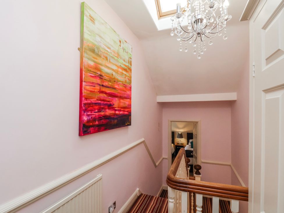 A hallway with a staircase and painting at 50 West Street Edelweiss in Scarborough