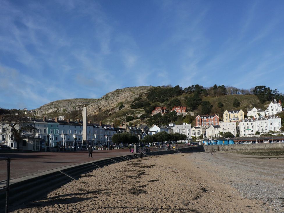 A beach with buildings and a hill at The Keep in Llandudno