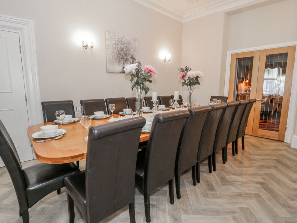 A dining room with a long table set for dinner at The Keep in Llandudno